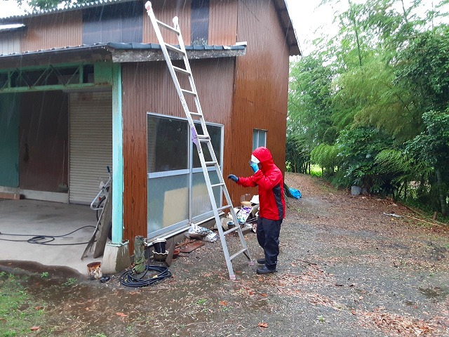高圧洗浄するのに屋根に上る様子